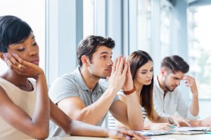Multiethnic group of tired bored business people sitting on business meeting in office